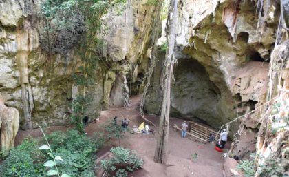 The cave in the forest in Kenya with the excavation team working at the mouth